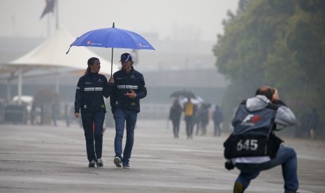 Pembalap Sauber, Antonio Giovinazzi (kedua kiri) berjalan di sirkuit Shanghai yang diguyur hujan, Kamis (6/4). Sesi latihan bebas GP Cina pada hari ini dibatalkan akibat cuaca buruk.