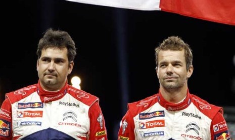   Pembalap Sebastien Loeb dari Prancis (kanan) bersama co-driver Daniel Elena dari Monaco (kiri) di podium saat merayakan kemenangannya dalam Rally de France di Strasbourg, Perancis, Ahad (7/10).