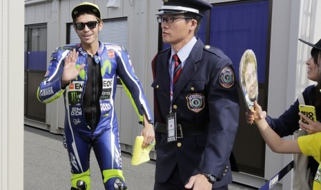 Pembalap Yamaha Movistar, Valentino Rossi (kiri) melambaikan tangan kepada fan saat sesi latihan bebas MotoGP di sirkuit Motegi, Jepang, Jumat (14/10). Rossi berada di urutan ketujuh.