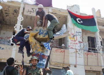 Pemberontak memanjat monumen di kamp kediaman Moammar Qaddafi, Bab Al-Aziziya, di Tripoli, Kamis (25/8). Keberadaan Qaddafi dan keluarganya belum diketahui.