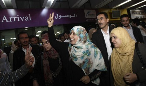  Pemenang nobel perdamaian asal Yaman, Tawakul Karman mengangkat kedua jarinya saat tiba dari Mesir, di Bandara Internasional Sanaa,Yaman, Ahad (4/8).  (AP/Hani Mohammed)