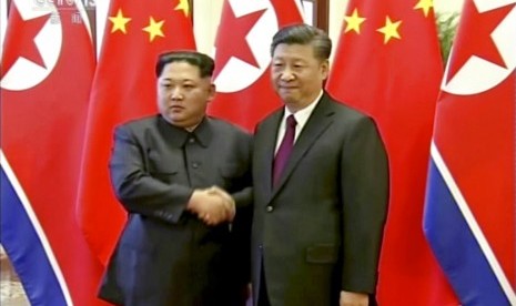 Pemimpin Korea Utara, Kim Jong-un bersalaman dengan Presiden Cina Xi Jinping saat bertemu di Beijing, Rabu (28/3).