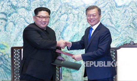 Pemimpin Korea Utara Kim Jong Un, kiri, dan Presiden Korea Selatan Moon Jae-in berjabat tangan setelah menandatangani pernyataan bersama di desa perbatasan Panmunjom di Zona Demiliterisasi, Korea Selatan, Jumat (27/4).