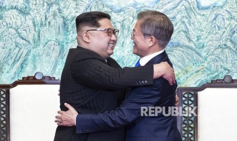 Pemimpin Korea Utara Kim Jong Un, kiri, dan Presiden Korea Selatan Moon Jae-in saling berpelukan setelah menandatangani pernyataan bersama di desa perbatasan Panmunjom di Zona Demiliterisasi, Korea Selatan, Jumat (27/4).