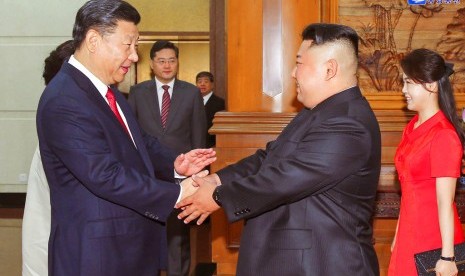 Pemimpin Korea Utara (Korut) Kim Jong-un (kedua dari kiri) berjabat tangan dengan Presiden Cina Xi Jinping di Diaoyutai State Guesthouse, Beijing, Rabu (20/6). Foto dipublikasikan pada Kamis (21/6). paling kanan adalah istri Kim, Ri Sol Ju.