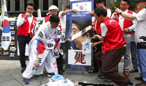 Pemrotes Korea Selatan (Korsel) menggunting foto Perdana Menteri Jepang Shinzo Abe dalam protes mengecam Jepang yang membatasi ekspor ke Korsel di depan Kedubes Jepang di Seoul, Korsel, Selasa (23/7). 