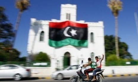 Pemuda Libya mengacungkan jari tangan tanda kemenangan ketika melintas di depan gedung Al-Ajaylat yang kini dikuasai pemberontak, sekitar 120 kilometer barat Tripoli, Libya.