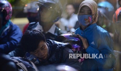 Pemudik beristirahat saat antre untuk memasuki kapal tujuan Bakauheni di Pelabuhan Merak, Banten, Ahad (3/7) dini hari. Puncak arus mudik di Pelabuhan Merak diperkirakan terjadi pada hari ini Sabtu (2/7) hingga Ahad (3/7). 