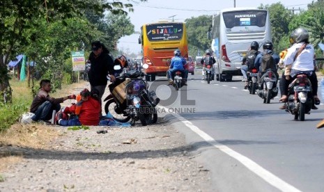 Pemudik motor beristirahat di bahu jalan Pantura, Indramayu, Jawa Barat, Selasa (14/7). Panasnya cuaca ditambah lamanya perjalanan membuat para pemudik motor sejenak beristirahat untuk menghilangkan lelah dan kantuk