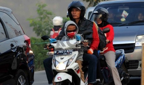  Pemudik motor membawa anak mereka yang masih kecil saat melintas di kawasan Karawang, Jawa Barat.