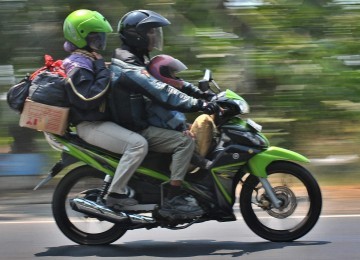 Pemudik sepeda motor dengan tiga penumpang melintas di Jalan Raya Mangkang Semarang, Jateng, Sabtu (27/11). Masih banyak pemudik sepada motor yang tidak menghiraukan larangan lebih dari dua orang. 