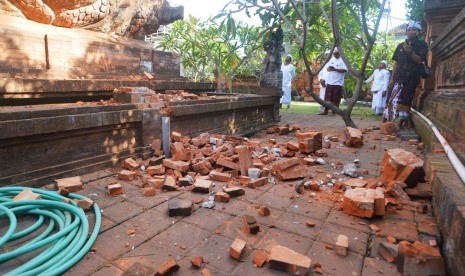 Pemuka agama Hindu memantau kerusakan pada bagian candi yang runtuh akibat gempa di Pura Lokanatha, Denpasar, Bali, Selasa (16/7/2019).