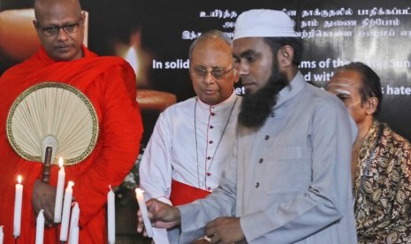 Pemuka agama Islam Sri Lanka menyalakan lilin dalam acara solidaritas kepada korban pengeboman saat Paskah di Kolombo, Sri Lanka, Ahad (28/4). Di belakangnya tampak biksu Budha, biksu Hindu, dan pendeta Kristen.