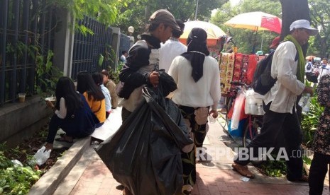 Pemulung bernama Wahyu (30) mengumpulkan kemasan bekas makanan dan minuman berbahan plastik di sekitar Masjid Istiqlal, Ahad (2/12).