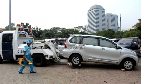 Penampuangan Derek Parkir Liar. Petugas menggembok ban mobi hasil razia parkir di Parkir IRTI Monas, Jakarta Pusat, Rabu (1/7). (Republika/Wihdan)