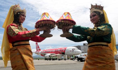 Penari tradisional Aceh Ranub Lampuan berada di depan maskapai Air Asia saat kedatangan perdananya di Bandara Sultan Iskandar Muda, Aceh Besar, Aceh, Senin (3/10/2022). Air Asia kembali melayani rute internasional setelah mendapat persetujuan dari Kementerian Perhubungan dari Bandara Sultan Iskandar Muda (BTJ) - Kuala Lumpur (KUL) yang selama dua tahun lebih terhenti akibat pandemi COVID-19.