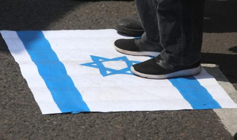 Pendemo di depan gedung DPRD Jawa Timur, Kota Surabaya pada Senin (17/5), menginjak bendera Israel.