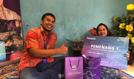 Pendiri dan CEO Amartha, Andi Taufan Garuda Putra memberikan hadiah kepada perempuan pengusaha mikro.