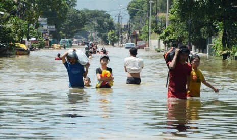 Penduduk berjalan digenangan banjir luapan Sungai Citarum yang menggenangi Jalan Moh Toha, Kabupaten Bandung, Selasa (15/3). (Republika/Edi Yusuf)