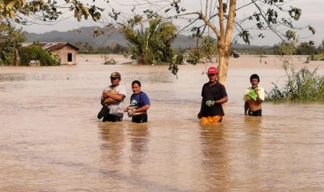 Penduduk desa di Filipina berjalan saat banjir akibat Topan Phanfone. Sedikitnya 28 orang dipastikan meninggal dunia akibat Topan Phanfone di Filipina.