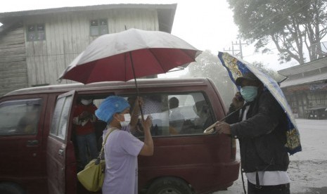  Penduduk desa menggunakan masker dan payung untuk melindungi diri dari abu vulkanik letusan Gunung Sinabung saat mereka meninggalkan rumah mereka di Karo, Sumatera Utara, Selasa (17/9).     (AP/Binsar Bakkara)