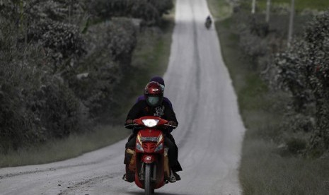  Penduduk desa naik sepeda motor melintasi jalan raya yang tertutup abu Gunung Sinabung di Desa Sigarang Garang di Kabupaten Karo, Sumut, Senin (25/11).     (Reuters/Beawiharta)