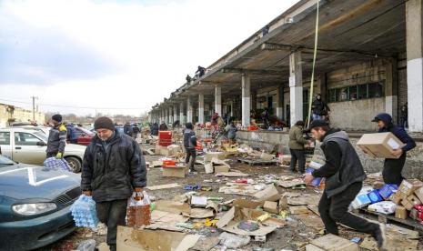 Penduduk lokal membawa air dari gudang makanan, di wilayah yang berada di bawah kendali Pemerintah Republik Rakyat Donetsk, di pinggiran Mariupol, Ukraina, Jumat (18/3/2022).