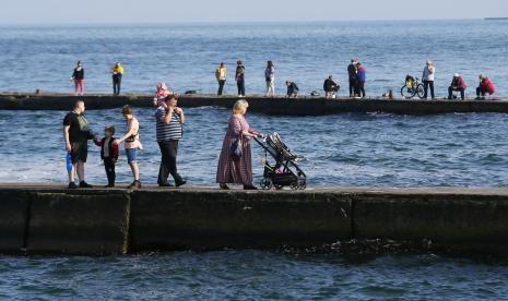 Penduduk setempat berjalan di pemecah gelombang dekat pantai tertutup di Odesa, Ukraina, 29 Mei 2022. Beberapa pantai di Kota Odesa, Laut Hitam Ukraina, telah resmi dibuka untuk pertama kalinya sejak invasi Rusia Februari tahun lalu. 