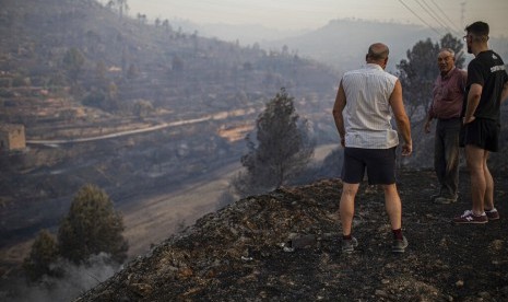 Penduduk setempat melihat hutan yang terbakar akibat cuaca panas ekstrem di Torre de l'Espanyol, dekat Tarragona, Spanyol, Kamis (27/6). 