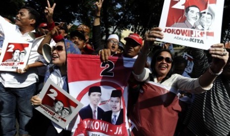 Pendukung Capres Joko Widodo dan Cawapres Jusuf Kalla memegang poster dengan urut dua usai penentuan nomor urut pasangan capres dan cawapres pada pilpres pada 9 Juli mendatang di depan Gedung KPU Jakarta, Ahad (1/6). 