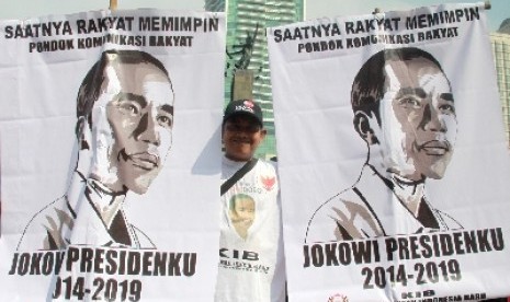 Pendukung Capres Joko Widodo dan Cawapres Jusuf Kalla memegang poster dengan urut dua usai penentuan nomor urut pasangan capres dan cawapres pada pilpres pada 9 Juli mendatang di Bundaran HI, Jakarta, Ahad (1/6).