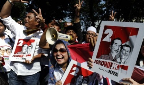 Pendukung Capres Joko Widodo dan Cawapres Jusuf Kalla memegang poster dengan urut dua usai penentuan nomor urut pasangan capres dan cawapres pada pilpres pada 9 Juli mendatang di depan Gedung KPU Jakarta, Ahad (1/6).