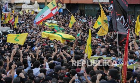 Pendukung Hizbullah dan Gerakan Amal membawa peti mati selama pemakaman tiga orang yang diduga tewas sehari sebelumnya oleh penembak jitu, di pinggiran selatan Beirut, Lebanon, 15 Oktober 2021.