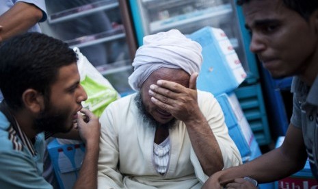   Pendukung Mursi mendampingi seorang warga yang meratapi kerabatnya yang tewas ditembak aparat keamanan di Nasr City, Kairo, Sabtu (27/7). (AP/Manu Brabo)   