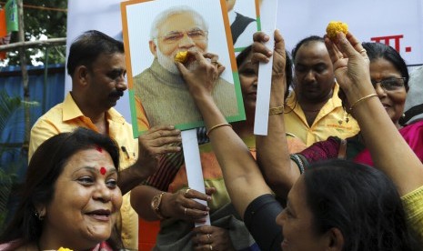 Pendukung Partai India Bhartiya Janata Party (BJP) membawa poster PM Narendra Modi merayakan pencabutan status istimewa Kashmir di Mumbai, India, Selasa (6/8).