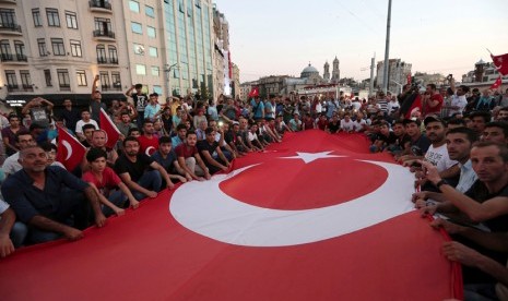 Pendukung Presiden Turki Tayyip Erdogan melambaikan bendera nasional Turki di Taksim Square Istanbul, Turki, (16/7) .