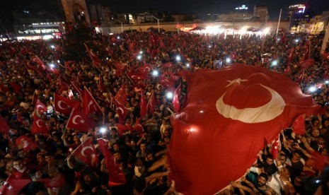  Pendukung Presiden Turki Tayyip Erdogan mengibarkan bendera nasional mereka berkumpul di Taksim Square di pusat kota Istanbul, Turki, (16/7).