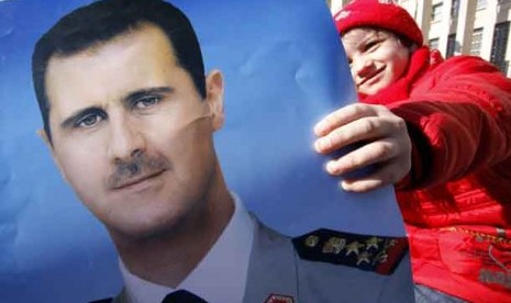 Pendukung rezim Suriah memegang poster Presiden Suriah Bashar Al-Assad.