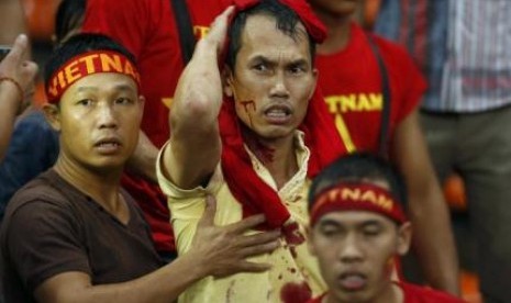 Pendukung Vietnam memegangi kepalanya yang terlukan terkena lemparan pendukung Malaysia dalam semifinal leg pertama Piala AFF 2014 di Kuala Lumpur, Ahad (7/12).