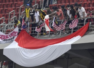 Pendukung Indonesia mengibarkan bendera usai kekalahan timnas