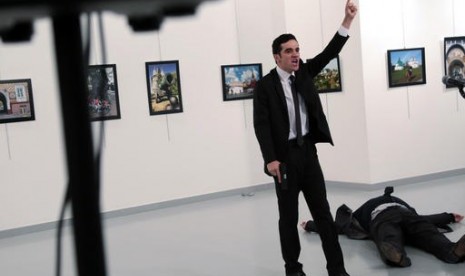 Penembak Dubes Rusia untuk Turki, Mevlut Mert Altintas usai menembak sang Dubes Andrei Karlov, di galeri foto di Ankara, Senin, 19 Desember 2016. Tampak Jasad Karlov tergeletak di sampingnya.