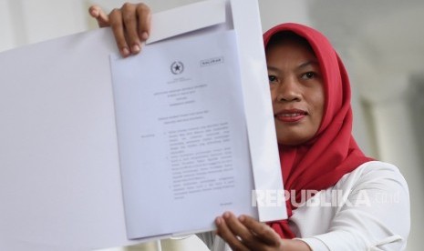 Penerima amnesti dari presiden, Baiq Nuril Maknun membawa salinan petikan keppres amnesti usai bertemu dengan Presiden Joko Widodo di Istana Bogor, Jawa Barat, Jumat (2/8/2019). 