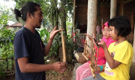 Pengajar Saung Singgah Kreatif tengah memberikan edukasi bermain angklung..