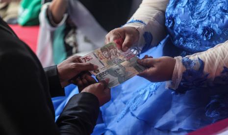 Pengantin menyerahkan mahar atau mas kawin dengan uang tunai Rp77 ribu saat melakukan prosesi akad pernikahan pada gelaran akad dan sidang isbat nikah massal gratis di Kecamatan Pahandut, Palangka Raya, Kalimantan Tengah, Senin (15/8/2022). Pemkot Palangka Raya memfasilitasi kegiatan tersebut bertujuan untuk meringankan beban masyarakat kurang mampu dalam mendapatkan legalitas dan administrasi pernikahan sesuai dengan ketentuan yang berlaku.