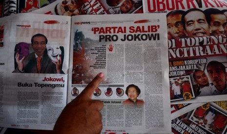 Pengasuh Pondok Pesantren Al Munawaroh, Muhtar Hudori menunjukkan tabloid Obor Rakyat edisi terbaru di Kelurahan Sumur Panggang, Tegal, Jateng, Ahad (6/7).