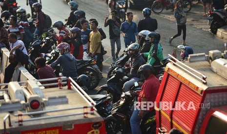 Pengedara sepeda motor yang melintas berhenti untuk melihat sejenak lokasi kebakaran Gedung Ramayana Pasar Minggu, Kamis (18/5)