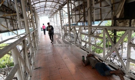 Pengemis tidur di Jembatan Penyeberangan Orang (JPO) di Jalan Rasuna Said, Jakarta, Kamis (26/11).