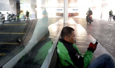 Pengemudi Gojek sedang membuka aplikasi handphone.