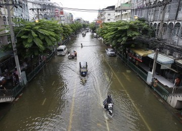 Pengemudi melintasi jalan yang terendam di Grand Palace di Bangkok, Thailand pada Jumat 28/10. (AP)