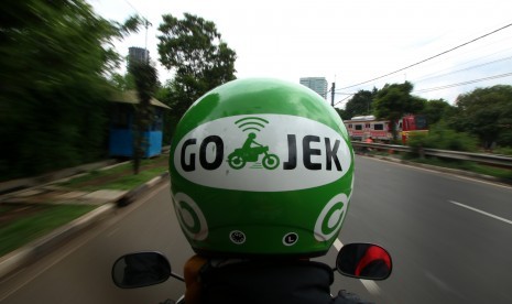  Pengemudi ojek berbasis online mengantar penumpang di kawasan Palmerah, Jakarta, Jumat (18/12). 